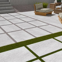 Grey porcelain patio tiles with grass joints in a UK garden